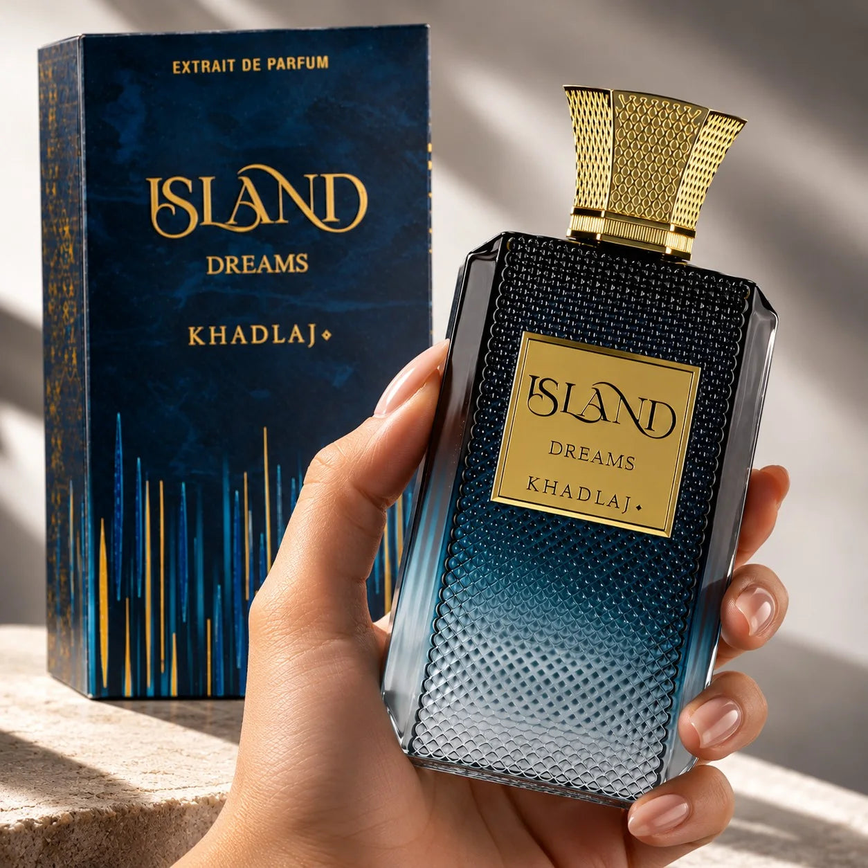 Frasco azul de Island Dreams Extrait de Parfum, com tampa dourada, segurado na mão ao lado da caixa original